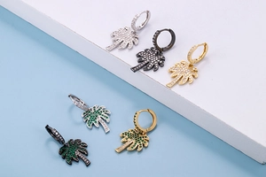 Detailed close-up of coconut tree earrings in gold, silver, and black with colorful zircons