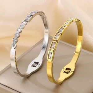 Close-up of gold and silver stainless steel bangles with alternating zircon stones