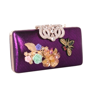 Detail of purple satin evening clutch with intricate crystal floral and bee jewel embellishments