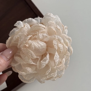 Close-up of beige tulle rose flower hair claw with elegant sheer organza fabric petals