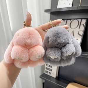 Close-up of pink and grey plush bunny keychains with fluffy fur and gold hardware