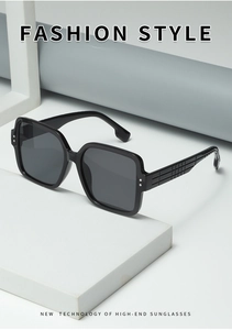 Close-up of oversized square sunglasses featuring grid-textured temples and metal studs