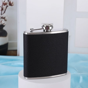 Close-up of 6oz stainless steel hip flask wrapped in black leather on a display stand