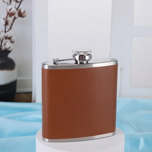 Detail of curved stainless steel hip flask wrapped in premium brown leather finish