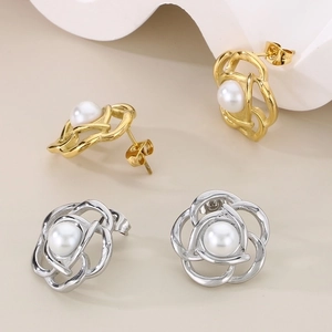 Detail of rose-shaped hollow metal earrings with a pearl center in gold and silver