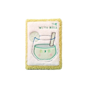 Funda de felpa amarilla para cuaderno con bordado de bebida verde y texto decorativo