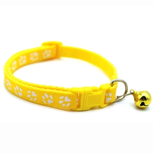Detail of yellow nylon pet collar featuring white paw prints, buckle, and golden bell