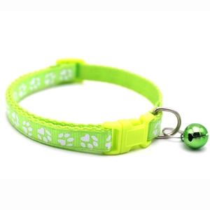 Detail of neon green pet collar with white paw prints, bell, and adjustable buckle