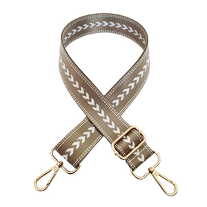 Adjustable brown nylon bag strap with white arrow patterns and gold hardware detail