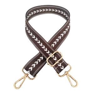 Detail of adjustable brown nylon strap with white herringbone pattern and gold metal hooks