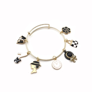 Dettaglio del bracciale dorato con corona di perle e ciondoli alla moda su sfondo bianco