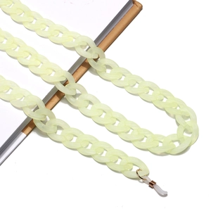 Close-up of frosted acrylic eyewear chain in pale yellow and green on a notebook