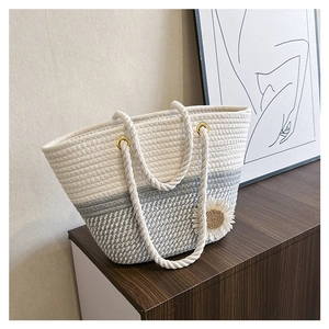 Detail of woven floral tote bag with daisy ornament and metallic hardware connectors