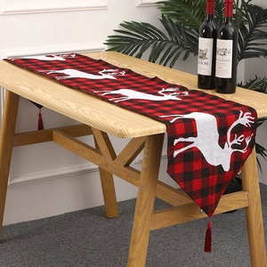 Detail of red and black buffalo plaid Christmas table runner with white reindeer and tassels