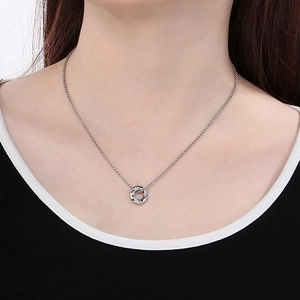 Close-up of interlocking silver ring pendant with sparkling crystals on a fine chain