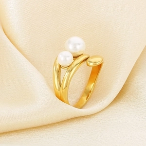 Detail of minimalist gold double-ring with two layered pearls on elegant satin