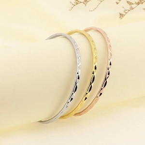 Macro detail of stacking titanium steel bangles with diamond-cut geometric patterns