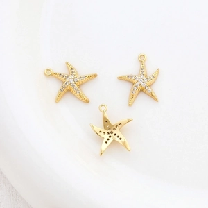 Macro detail of three 14k gold plated starfish charms with clear zircon inlay