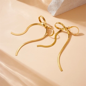 Elegant gold-plated bow earrings with long snake chain tassels on a stone background