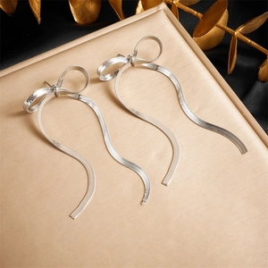 Elegant silver bow earrings with long snake chain tassels on a stylish tray