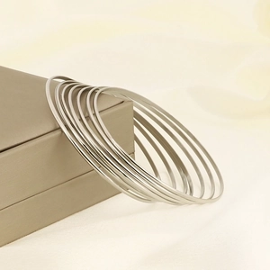 Set of 7 minimalist silver stainless steel bangles leaning on a jewelry box
