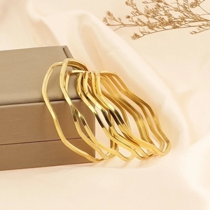 Minimalist gold wave bangle stack in polished stainless steel for modern women