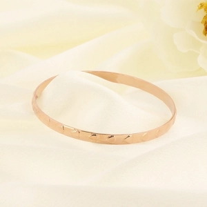 Polished gold plated titanium steel bangle with embossed heart patterns on silk background