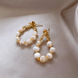 Detail of vintage gold pearl earrings on elegant champagne silk fabric background