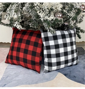Close-up of red and white plaid Christmas pillow covers by a festive tree