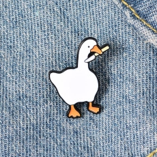 Macro detail of a white goose enamel pin with a dagger on denim background