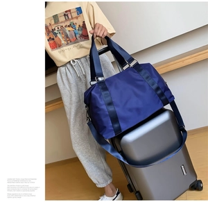 Detail showing the back luggage strap of a blue nylon travel bag on a suitcase handle