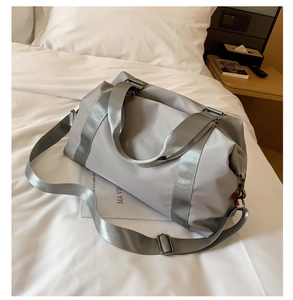 Close-up of waterproof grey fitness bag with durable handles on a hotel bed
