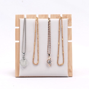 Close-up of heart and rhinestone pendants on bamboo and white leather jewelry display