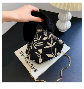 Macro detail of a black triangular handbag with gold floral brocade and faux fur handle