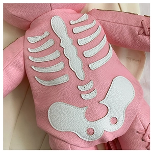 Detailed close-up of pink litchi grain leather with white skull applique and stitching