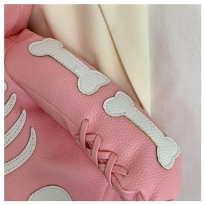 Detailed close-up of pink leather pet clothing featuring a white bone patch and woven ties