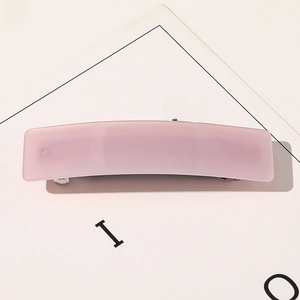 Gros plan d'une pince à cheveux rectangulaire rose mat avec détail de ressort en métal