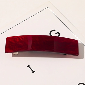 Gros plan sur la pince à cheveux rectangulaire rouge foncé en acétate avec texture marbre