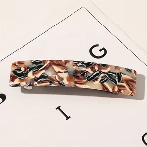 Détail macro d'une pince à cheveux carrée en acétate avec ressort métallique robuste