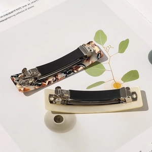 Détail de barrettes carrées en acétate ambré et résine crème avec ressorts métalliques