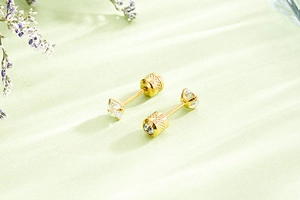 Detail of four-prong gold steel earring with threaded screw back and clear crystal stud