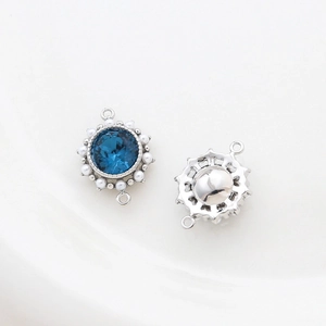 Detail view of 14k gold-plated round pendant with deep blue gem and white bead accents