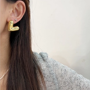 Minimalist 18K gold plated hollow heart studs shown on female model from side angle