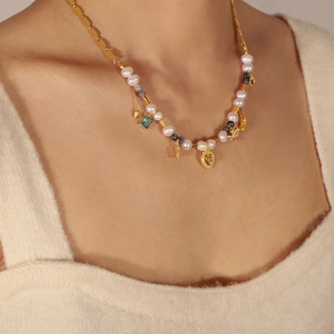 Detalle del collar de titanio dorado con perlas irregulares y colgantes de estrella