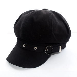Detail of black newsboy cap with metallic eyelets and decorative ring strap