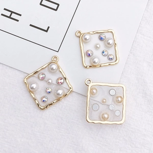Detailed view of square gold pendants featuring embedded pearls and rhinestones