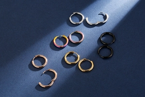 Close-up of five metallic hoop earrings in silver, gold, rose gold, black and purple