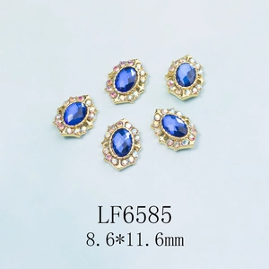 Détail de charmes d'ongles en strass bleu ovale avec monture dorée et cristaux AB