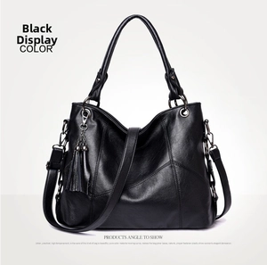 Detail of black pebbled leather tote bag with fringe charm and adjustable strap
