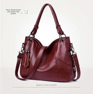 Detailed side view of a large burgundy leather tote bag with V-shaped stitching and tassel